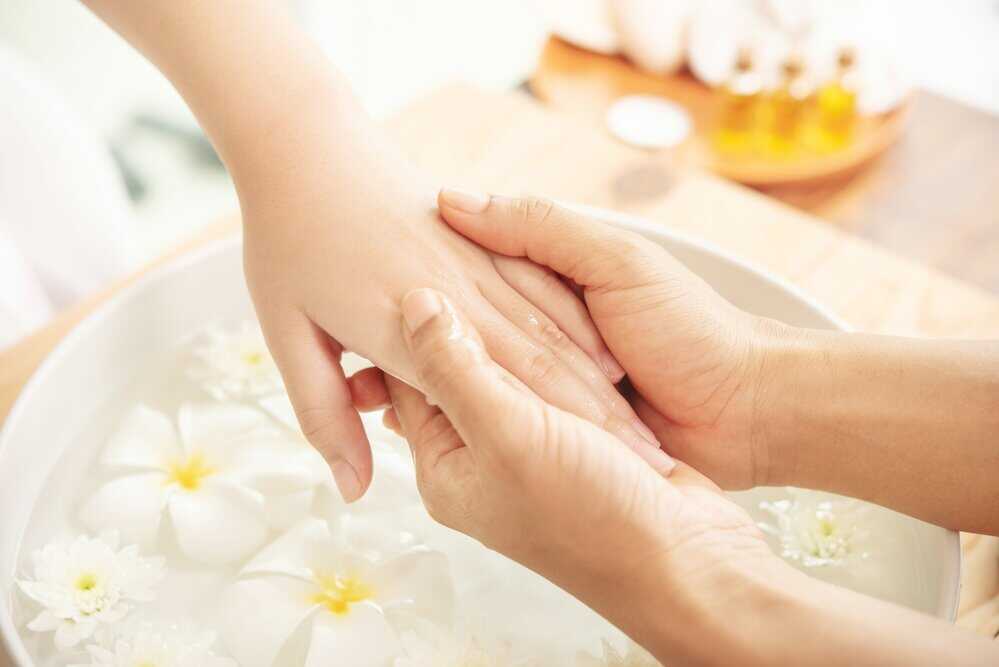 A beautician gives a patient a hand massage in a spa
