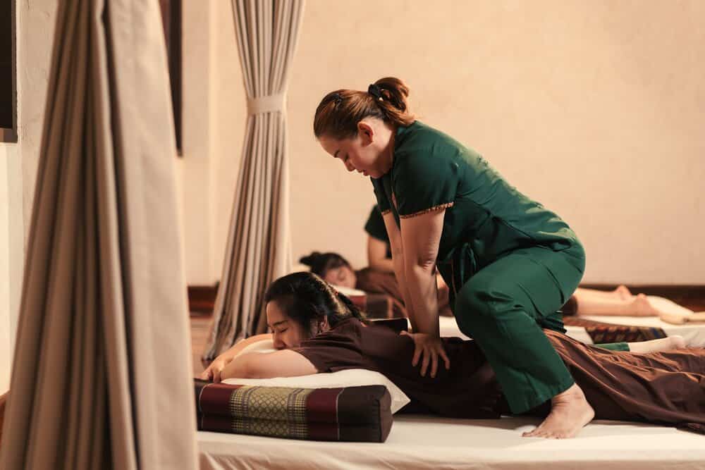 Thai masseuse applies pressure to her patient’s back to relieve stress and tension
