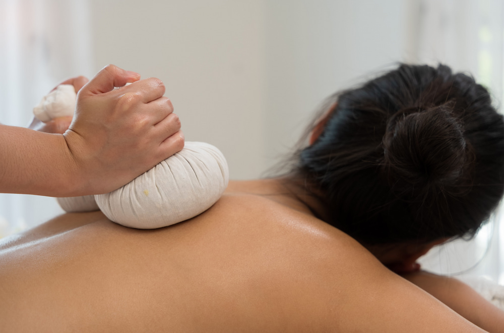 A woman receiving a Thai massage with herbal compress