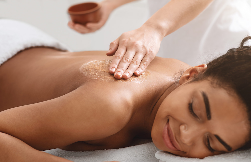 A woman getting a body scrub at a massage place by a therapist
