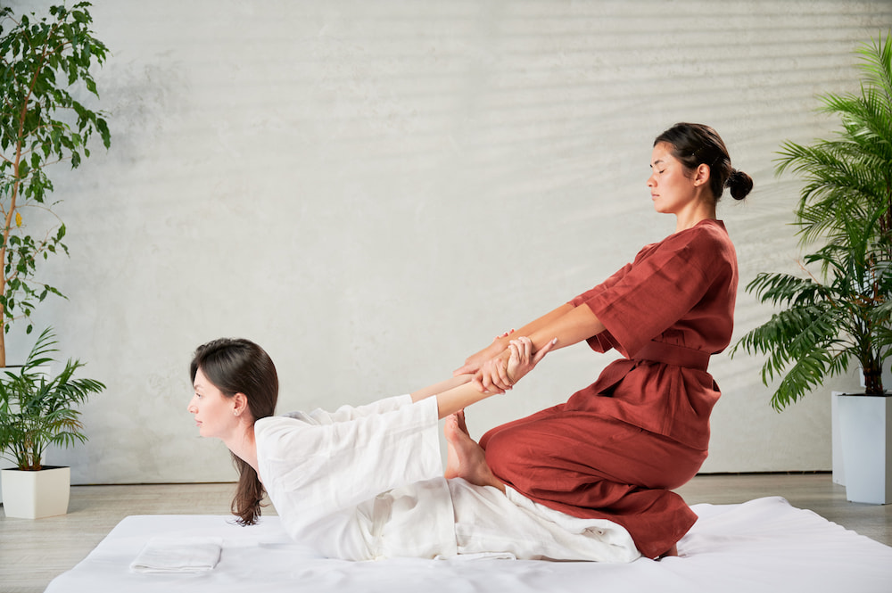 A masseuse stretching a patron during a Thai Warrior massage.
