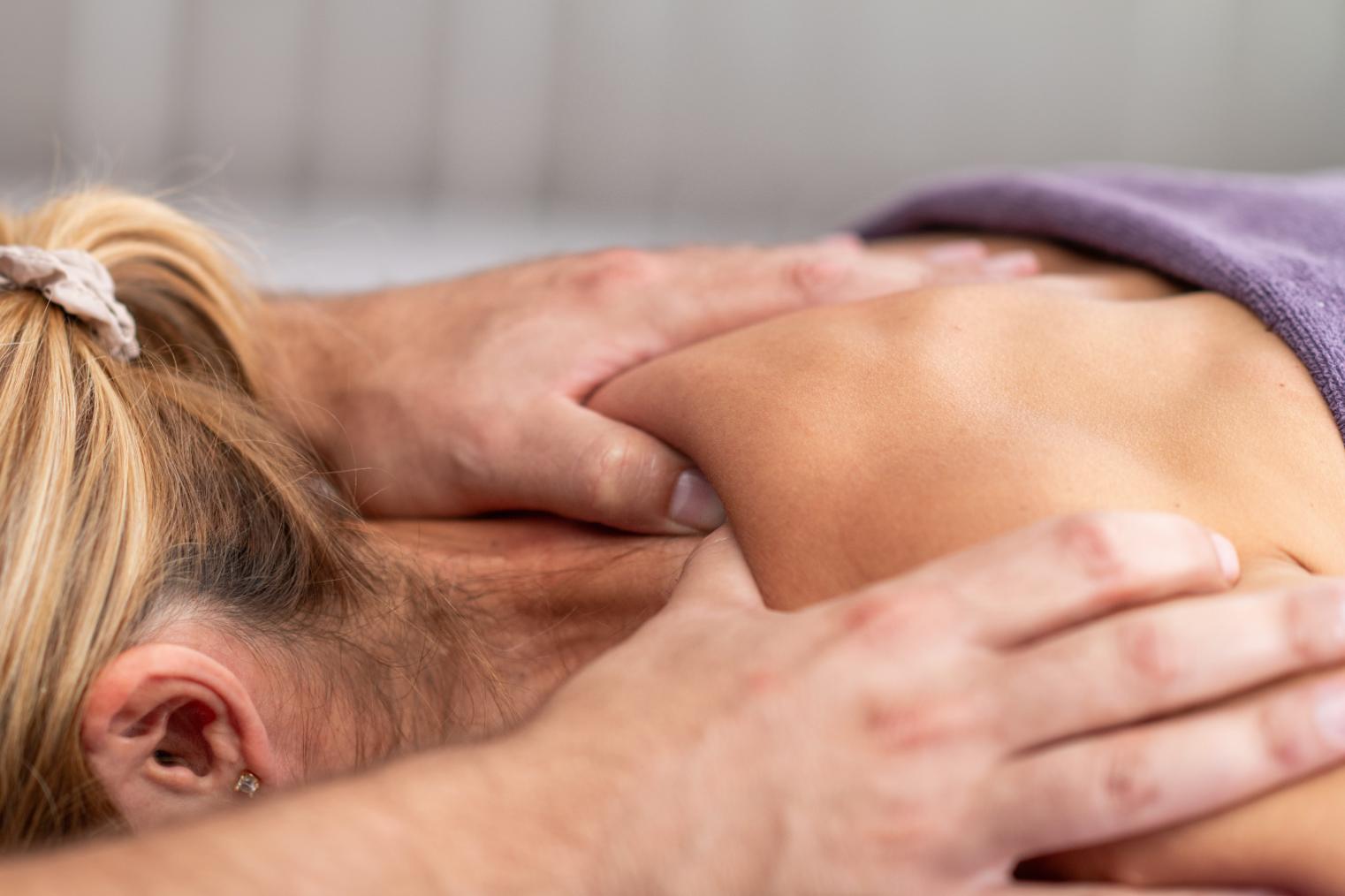 Therapist gives a post-workout massage on a woman's shoulder to ease muscle tension