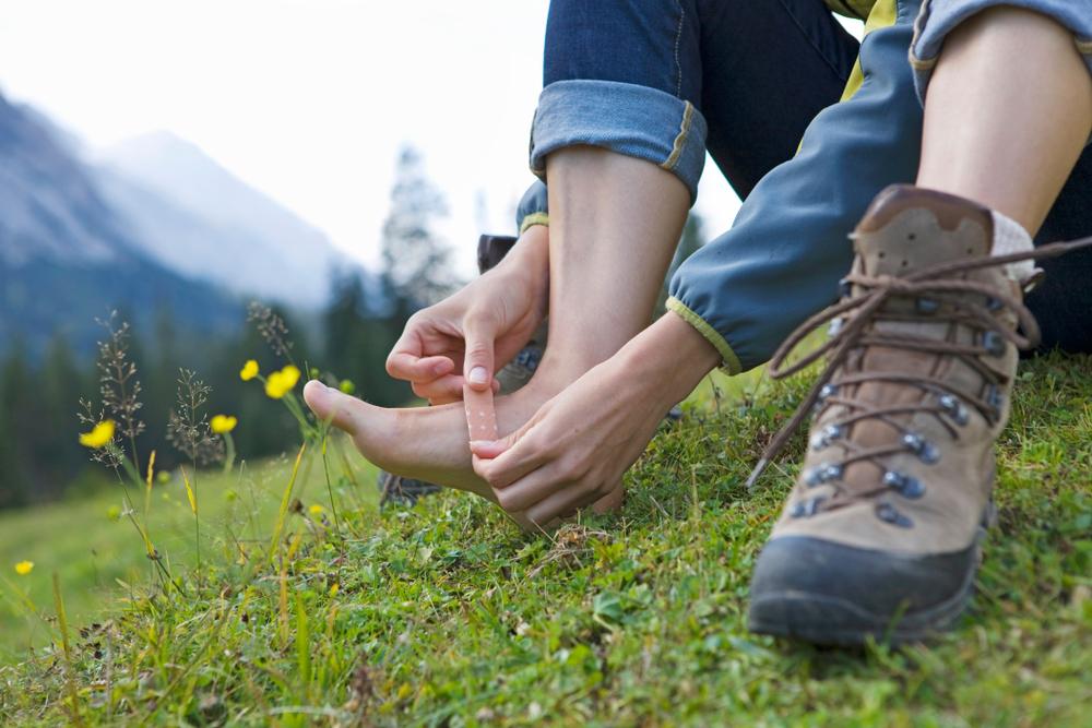 A woman using a plaster on her tired feet before a post-hike recovery massage.