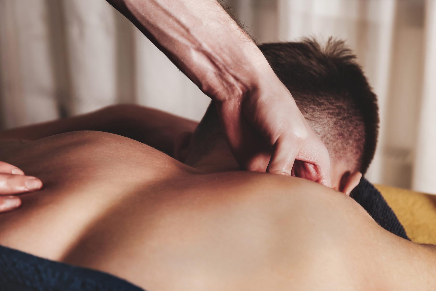 A therapist applying pressure point technique during a massage for back pain for tight muscles.