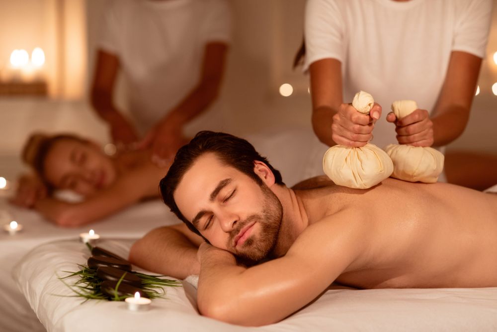 A couple relaxes during a herbal back massage. The right massage frequency helps for stress relief.