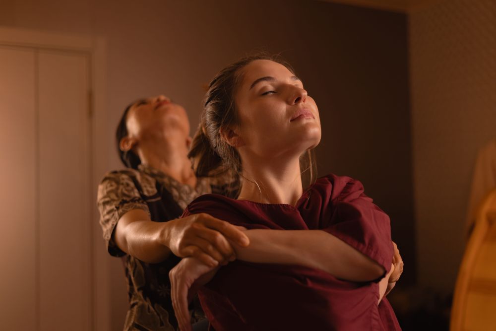 Woman receiving an assisted stretch from a therapist during a Thai massage