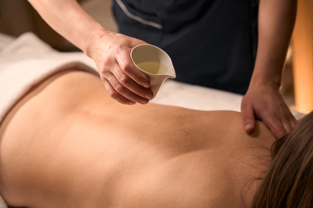 Warm herbal oil applied during an Ayurvedic massage.