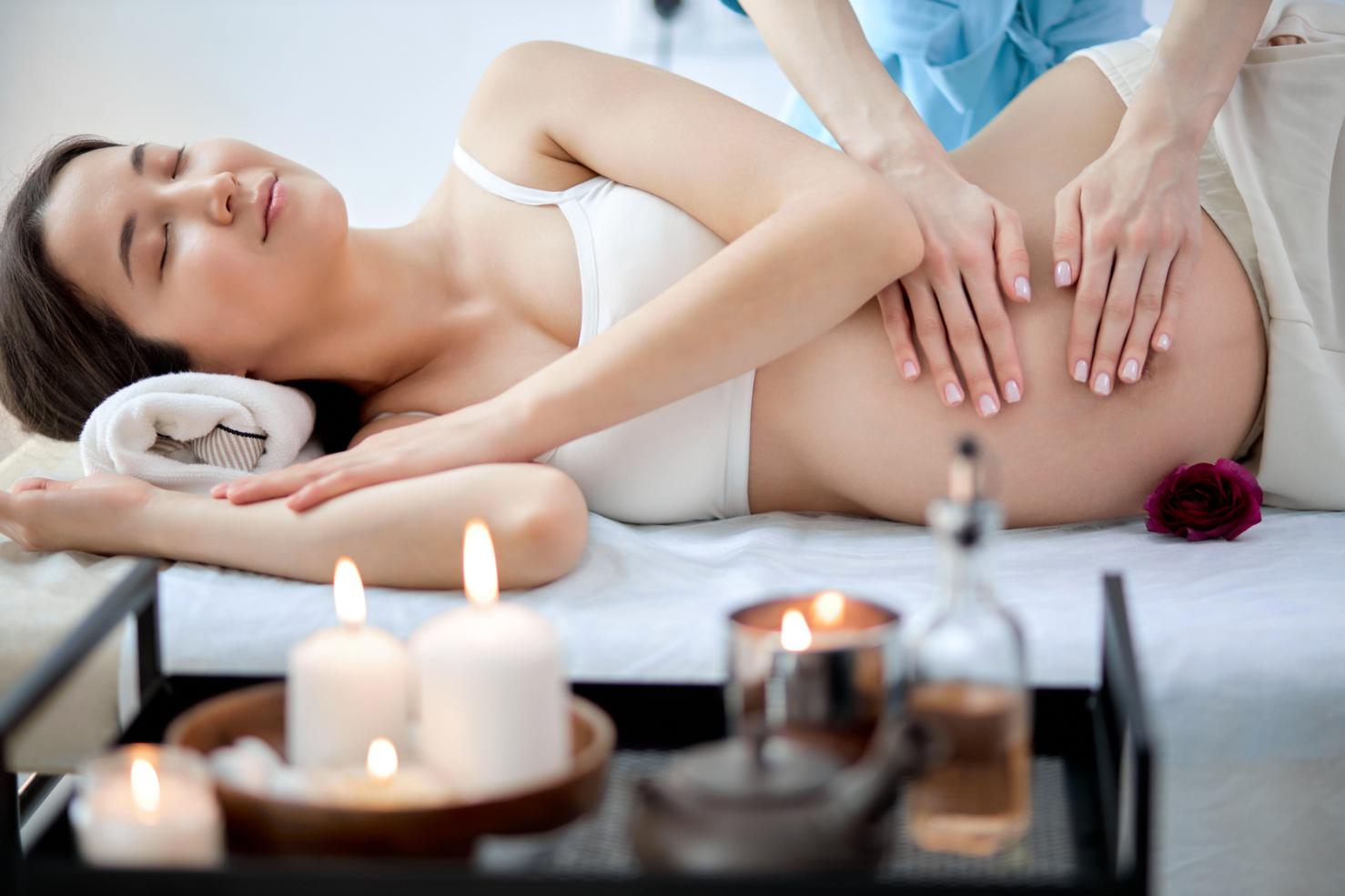 A woman receives a gentle massage during pregnancy in a side-lying position