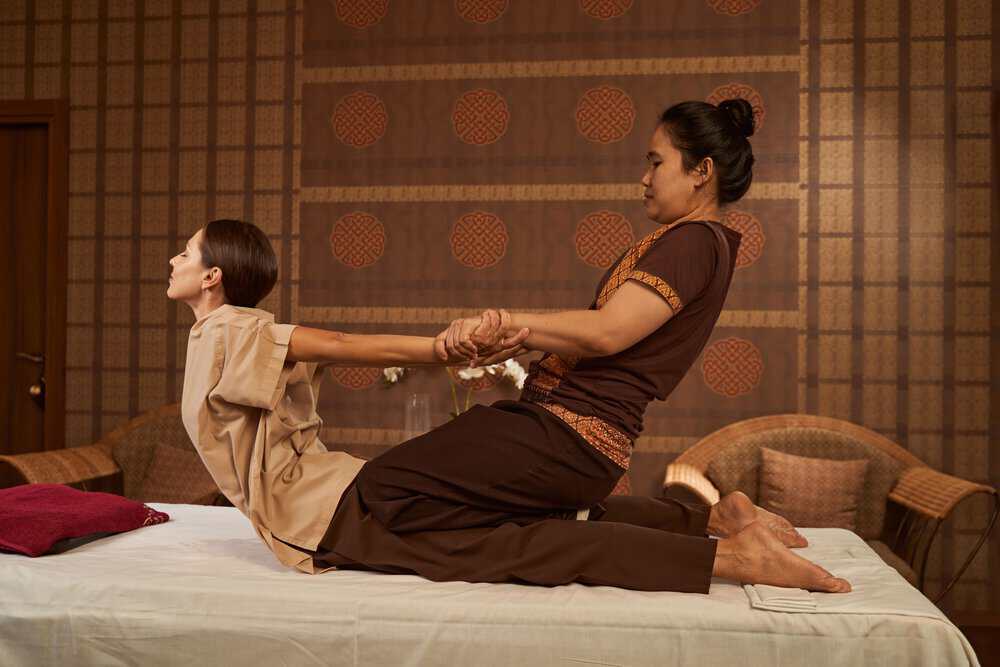 Thai masseuse stretches her client during a traditional Thai massage