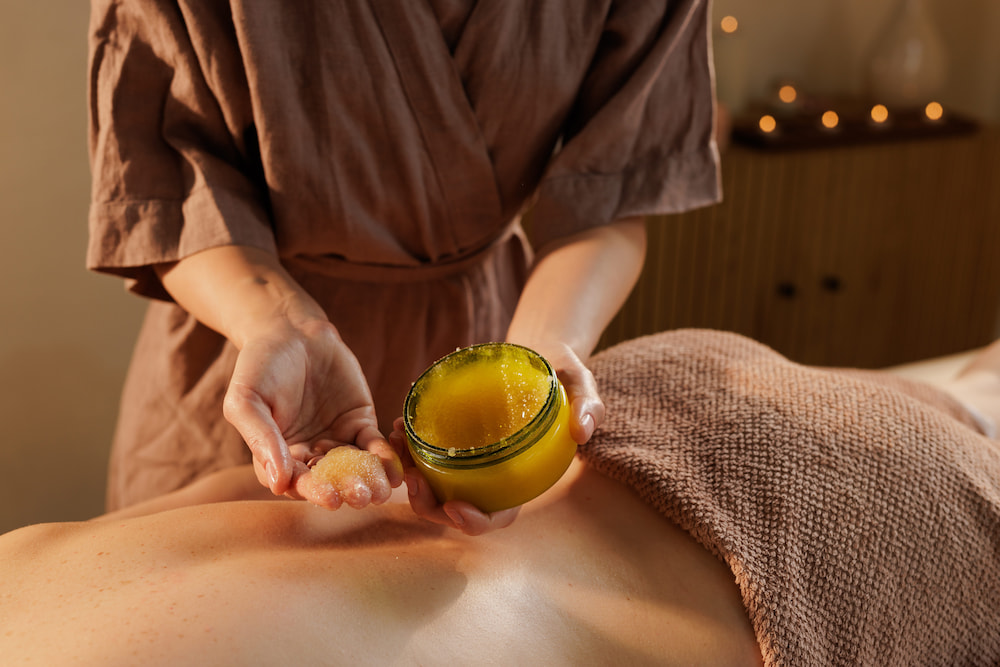 Therapist applying an exfoliating body polish treatment before beach season.