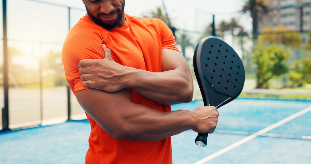 A man holding his shoulder in pain, a common reason for a sports recovery massage.