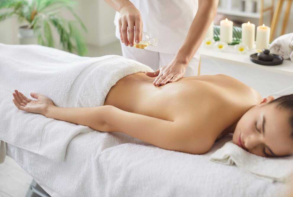 woman lays on her stomach ready to receive an oil massage on her back