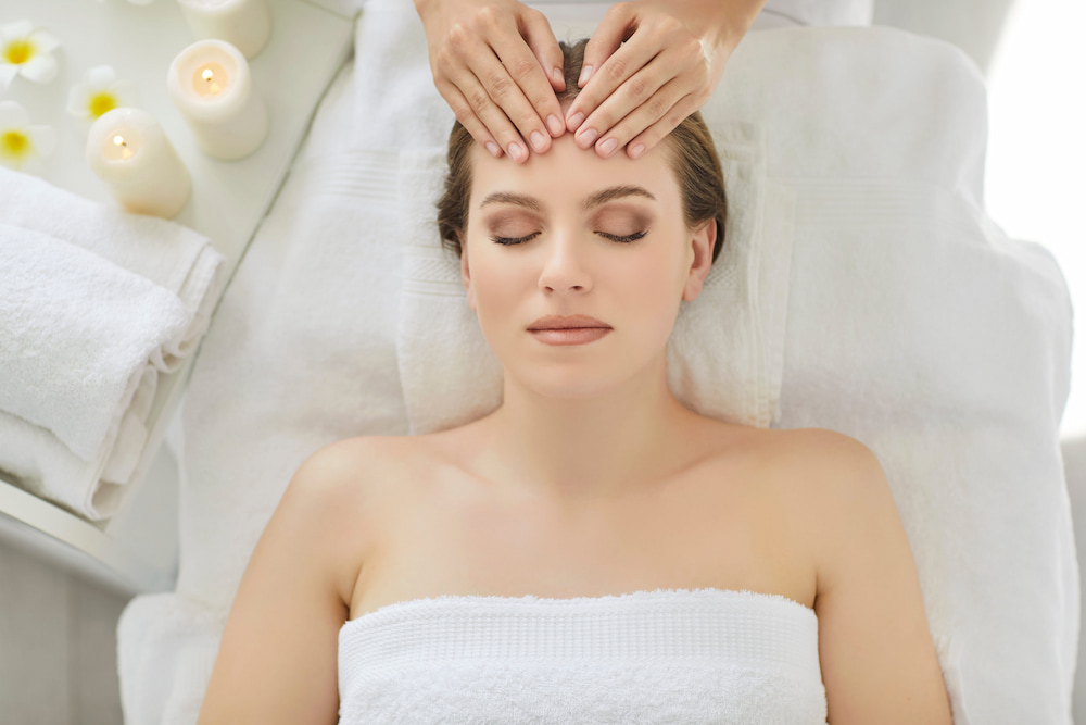 A woman receives a massage for headaches, with a gentle massage on the forehead for relief