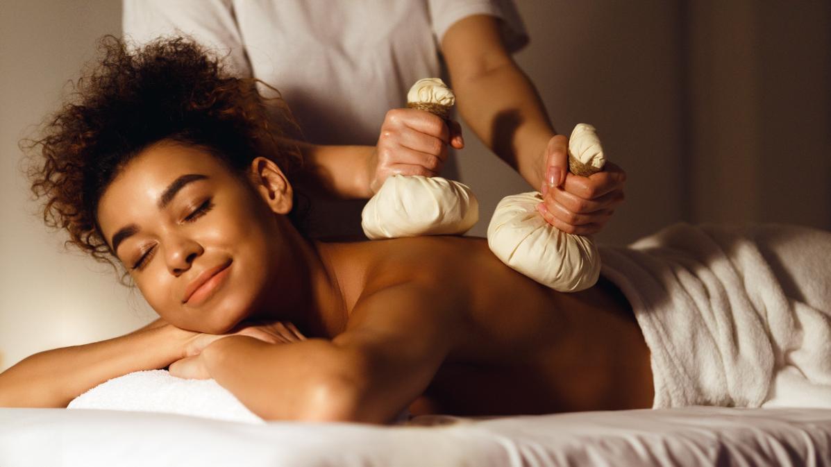 A woman benefits from a Thai Herbal Compress Massage