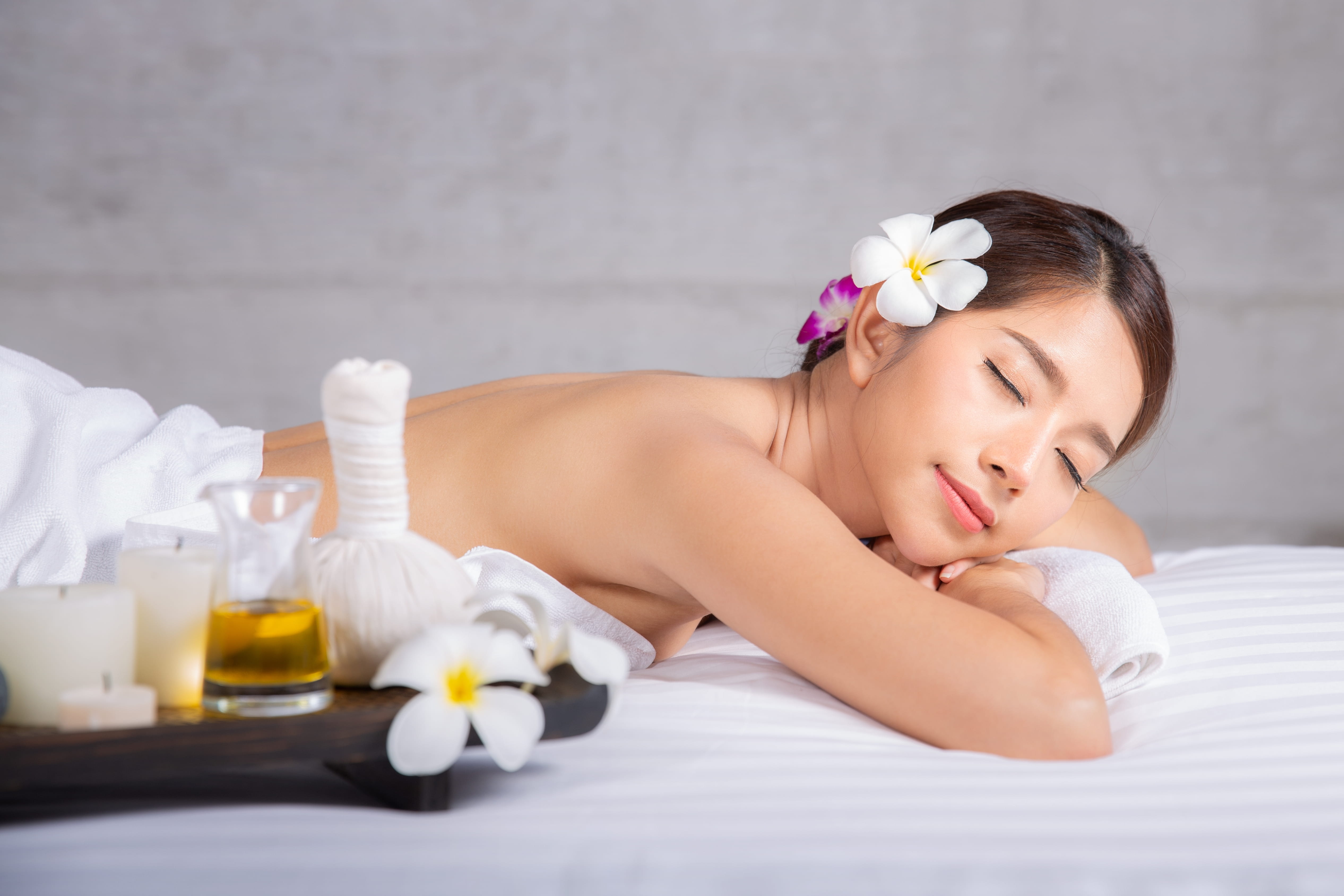 A woman relaxes during a gentle massage while on period days at a quiet aroma massage spa.