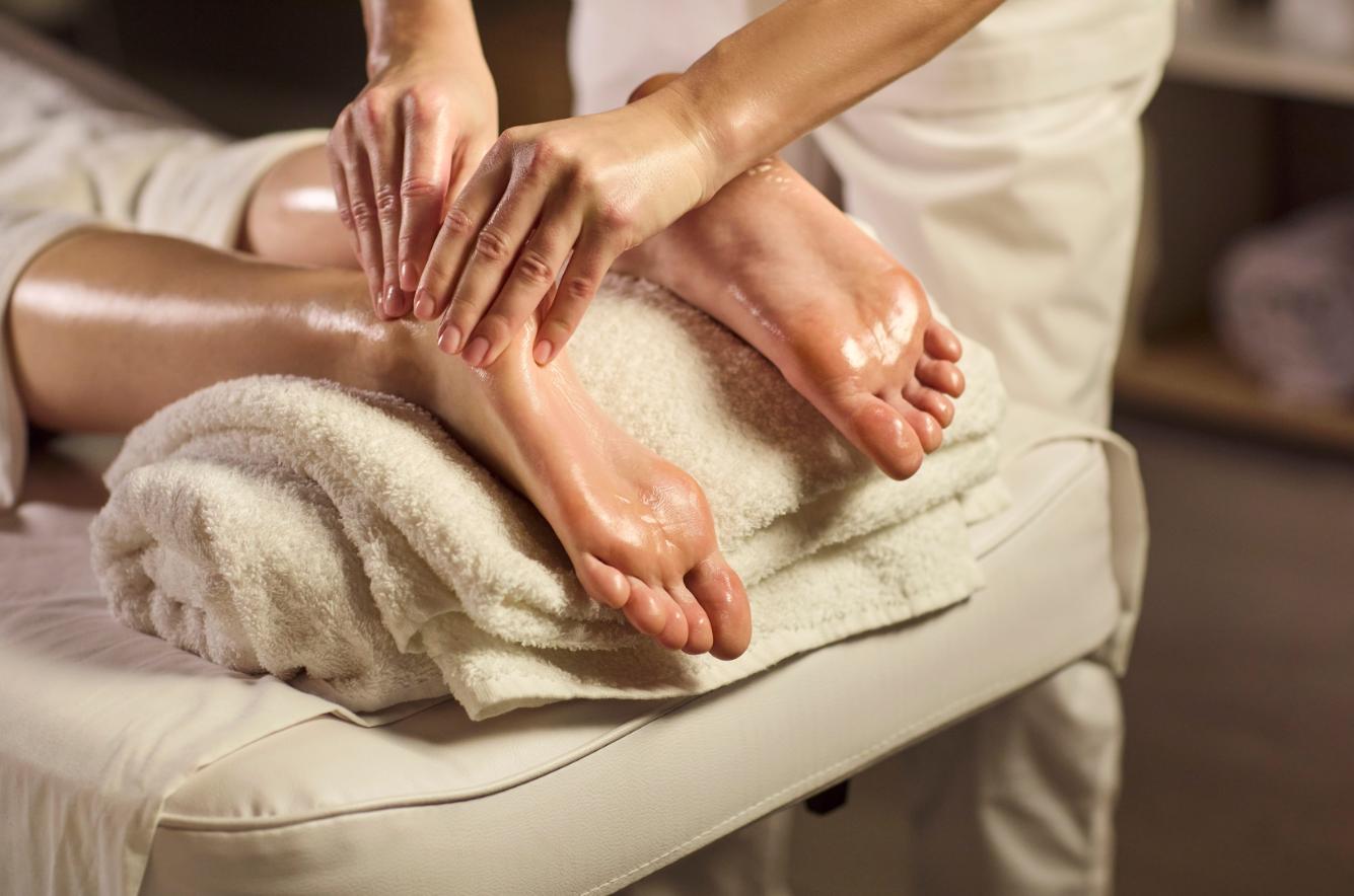 A therapist using effective leg massage techniques on a guest's calf and foot.